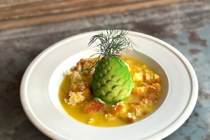 green pinecone-shaped dessert plated with fruit sauce and garnish